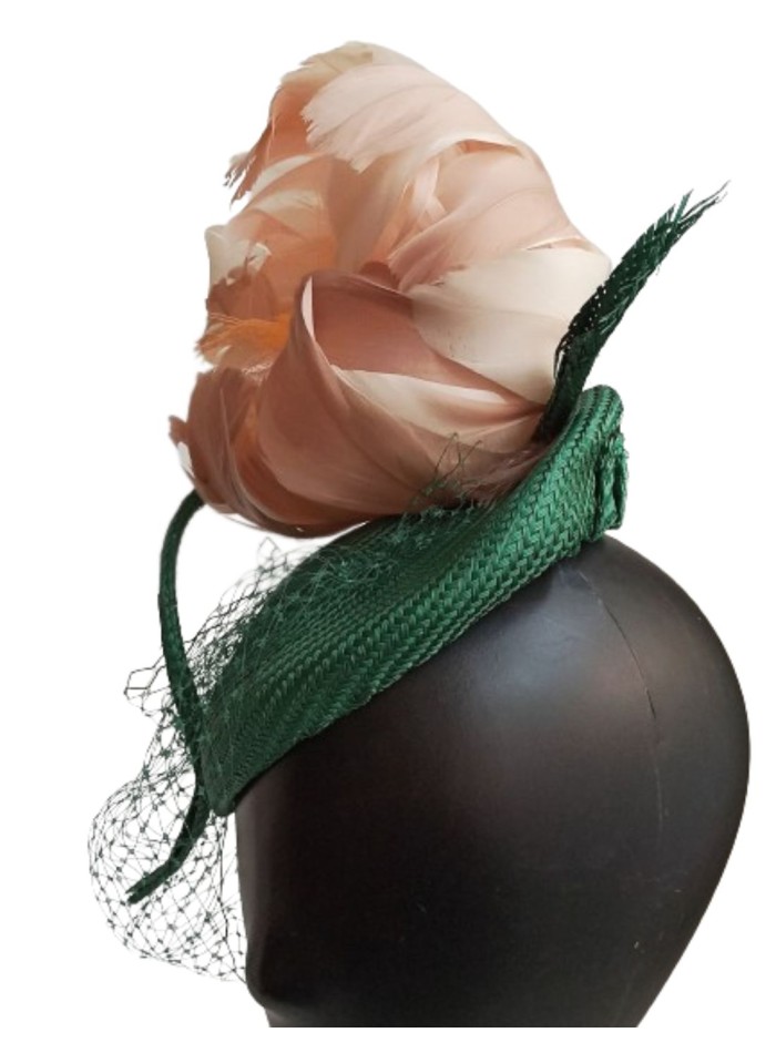 Tocado verde con flor de plumas en rosa.